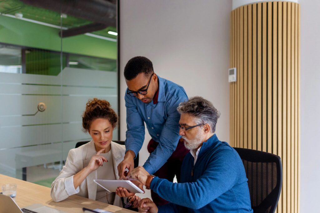 Three Business Professionals Collaborating on Tablet in Modern Office